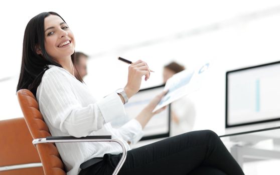 smiling business woman with financial documents sitting at work desk. business concept.