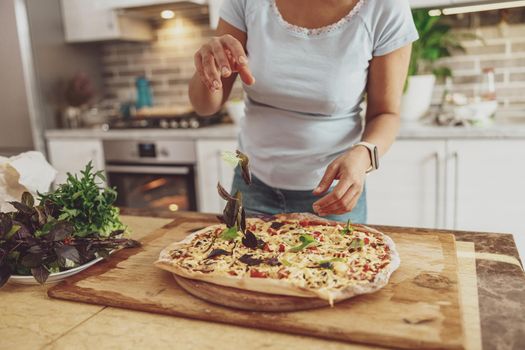 Cropped shot of woman making traditional homemade pizza at home