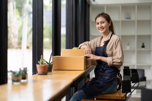 Starting a small business, SME owner, portrait female entrepreneur with products order online to prepare to pack a box of goods for sale to customers, sme business idea