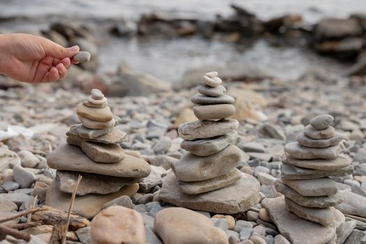 Pyramid of stones on the beach at sunset, beautiful seascape, rest and seaside vacation concept, banner panoramic view.Zen stones balance spa on beach.Balanced Pebbles Pyramid