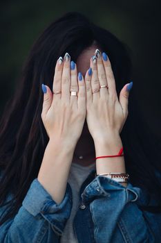 Girl with gorgeous dark long hair hiding face by arms.