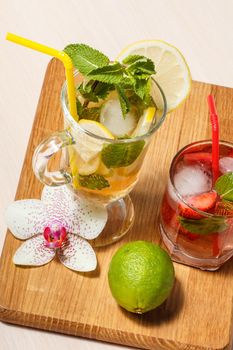 Glasses with cold lemonade mojito with lemon and mint and strawberry one
