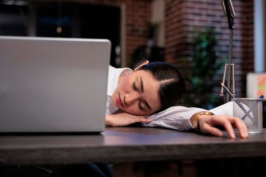 Exhausted agency worker falling asleep in office workspace while working on project.