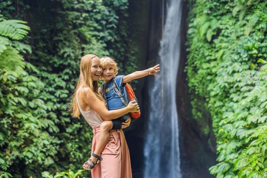 Mom and son travelers on the background of Leke Leke waterfall in Bali island Indonesia. Traveling with children concept