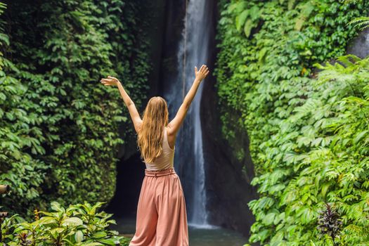Young woman tourist on the background of Leke Leke waterfall in Bali island Indonesia
