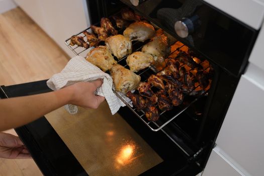 Woman take cooked chicken out of oven