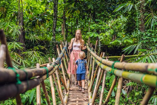 Mom and son travelers on the suspension bridge in Bali. Traveling with children concept.