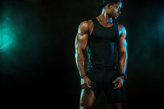 Sports men athlete on dark background. Power athletic guy bodybuilder doing fitness training.