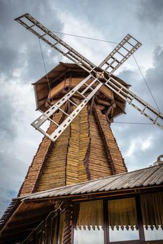 Windmill. Big wooden mill on cloudy sky background.