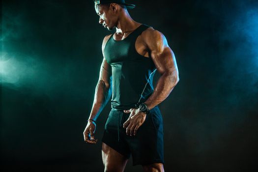 Sports men athlete on dark background. Power athletic guy bodybuilder doing fitness training.