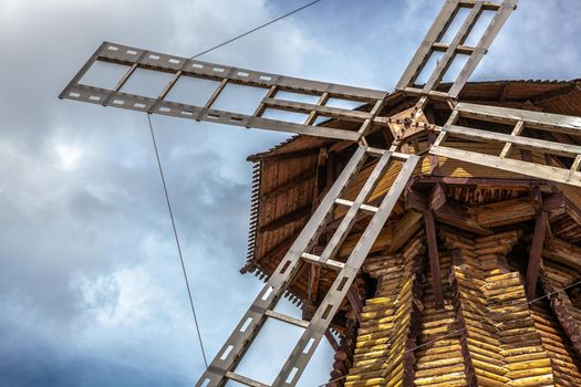 Windmill. Big wooden mill on cloudy sky background.