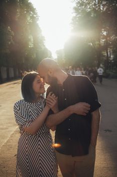 lovers take a walk in the park in the summer. the girl firmly holds the guy's hand. glare of the sun