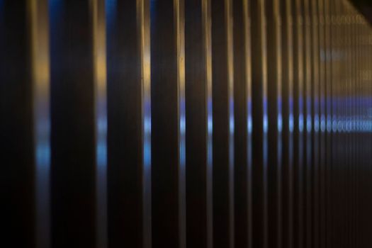 Reflection on metal fence. Warm and cool colors on steel profile. Fence at night.