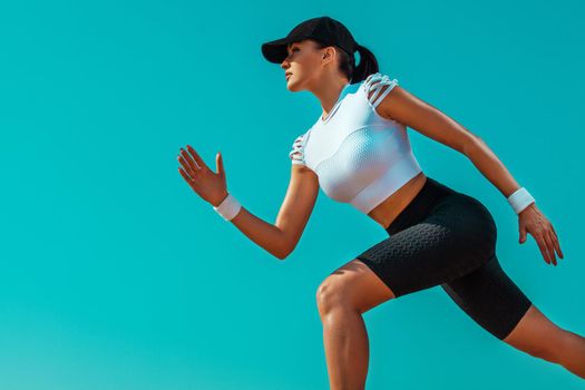 Athlete runner and sprinter. Girl fit athlete running on the sky background. The concept of a healthy lifestyle and sport. Woman in black and white sportswear.