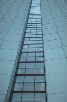 High-rise building on gray day. Architecture details. Surface of wall.