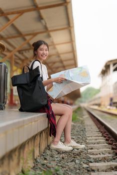 Young traveler woman looking on maps planning trip at train station. Summer and travel lifestyle concept.
