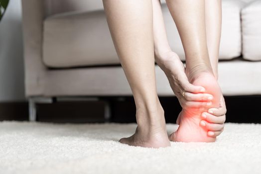 Asian woman standing feeling pain in her foot at home