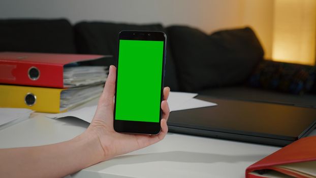 Woman at home relaxing reading on the smartphone with pre-keyed green screen, Chromakey Mockup.