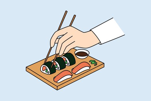 Person hold chopsticks eating sushi