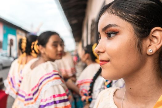Latin young woman dressed in traditional costume of Nicaraguan folklore with her group of friends in the background in Leon
