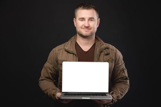 Studio portrait of a casual man holding an open laptop with a white cut-out screen in his hands. Website presentation or application copy space