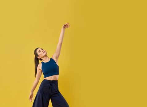 Stylish girl moving arm gracefully while dancing in studio.