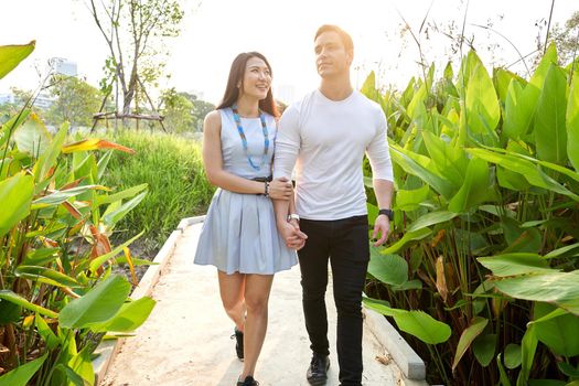 Multiracial couple walking on a path surrounded by tropical plants in a park