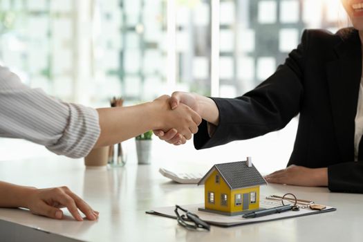 Real estate broker and customer shaking hands after signing a contract: real estate, home loan and insurance concept