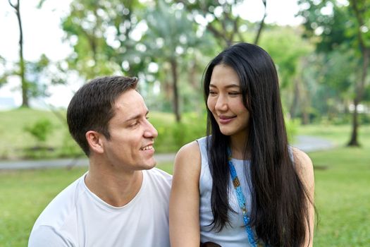 Close up portrait of a multiethnic couple smiling together in a park