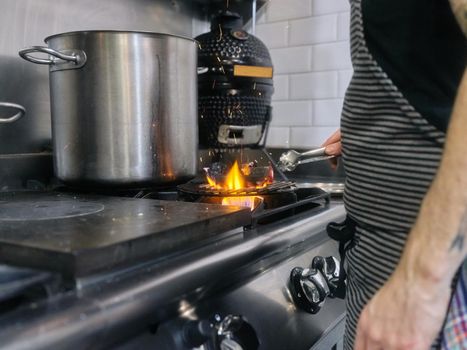Cook using tongs to remove charcoal that is on the fire in a restaurant