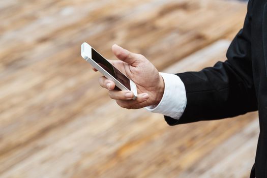 Close-up smart Business man wearing modern black suit and white shirt and texting on mobile smart phone.