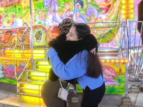 Two friends hugging each other in a night fair