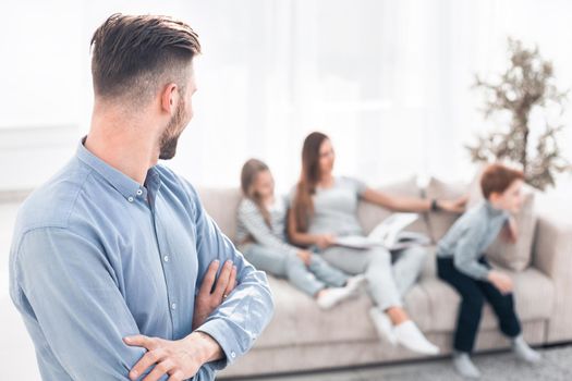 man standing in his living room and looking at his family