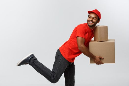 Delivery Concept - Handsome African American delivery man rush running for delivering a package for customer. Isolated on Grey studio Background. Copy Space.