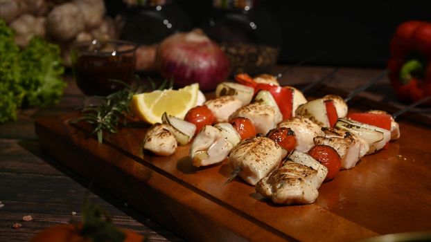 Delicious barbecue skewers chicken kebabs with vegetables on wooden plate