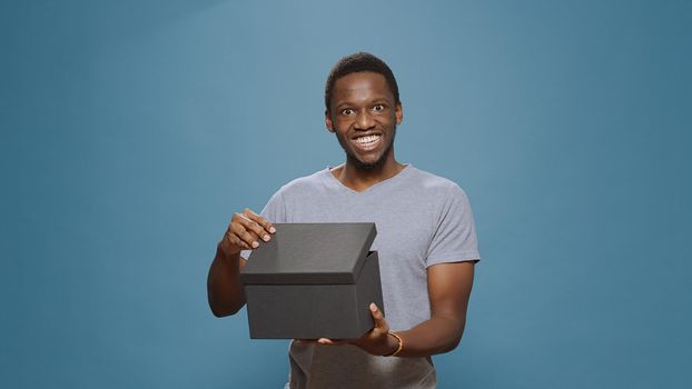 Cheerful man opening present box to see purchase on camera