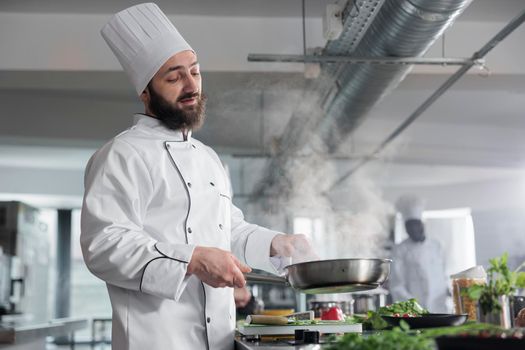 Gastronomy expert wearing cooking uniform while cooking delicious gourmet dish for dinner service.