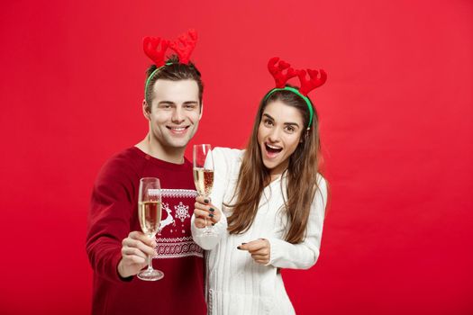 Christmas concept - Happy young couple in sweaters celebrating christmas with Champagne