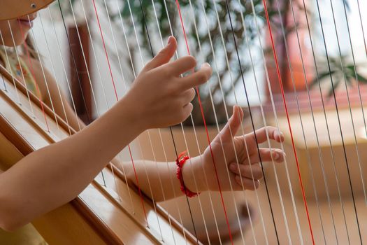 The child plays the harp. Selective focus. Kid.