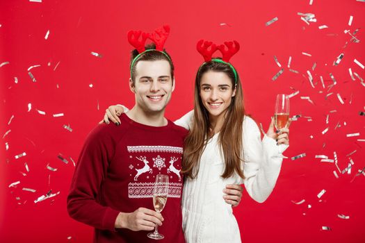 Christmas Concept - Happy caucasian man and woman in reindeer hats celebrating christmas toasting with champagne flutes, congratulating on xmas