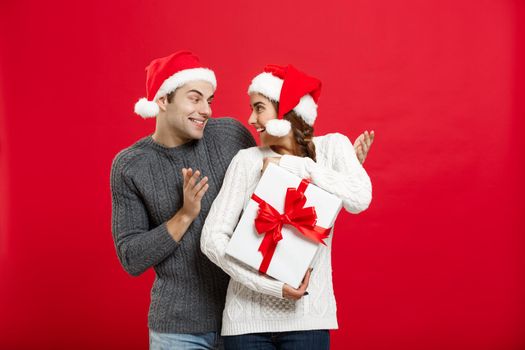 Christmas Concept - handsome young boyfriend in sweater surprise his girlfriend with white gift
