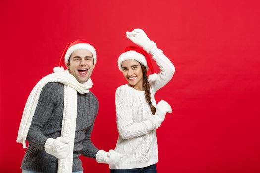 Christmas concept - Happy young couple in sweatesr celebrating christmas with playing and dancing