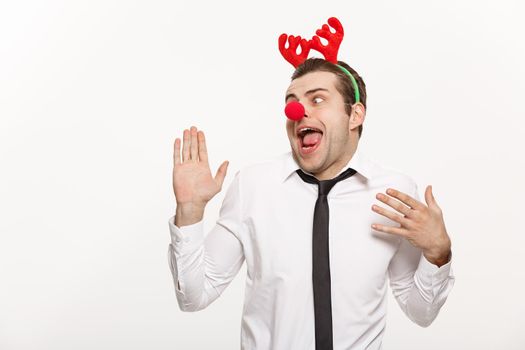 Christmas Concept - Handsome Business man wearing reindeer hairband making funny facial expression.