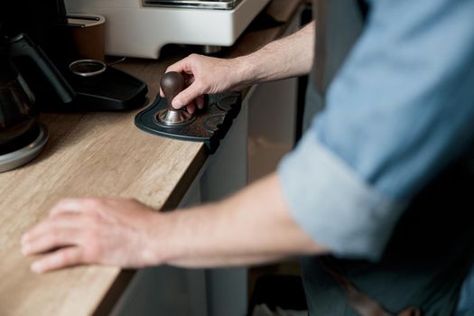 barista holding tamper standing behind a counter