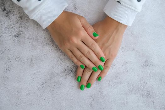 Manicured female hands with stylish green nails. Trendy modern design manicure. Gel nails. Skin care. Beauty treatment. Nail care. Trendy colors