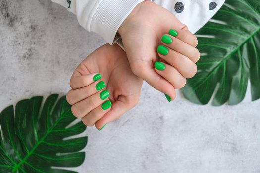 Manicured female hands with stylish green nails. Trendy modern design manicure. Gel nails. Skin care. Beauty treatment. Nail care. Trendy colors