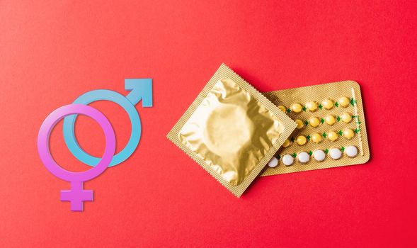 Male, female gender signs condom on wrapper pack and contraceptive pills blister hormonal birth control pills