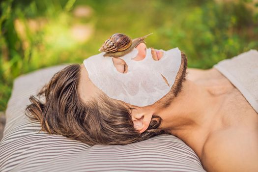 Young man makes a face mask with snail mucus. Snail crawling on a face mask. SPA for man, SPA for all