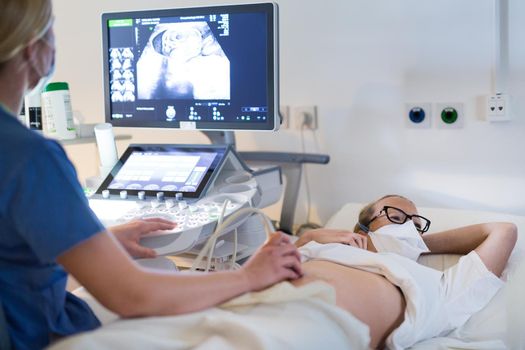 Close up of a pregnant woman having ultrasound scanning at the medical clinic. Healthcare and medicine concept