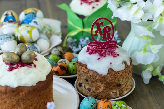 close up topper Easter cakes with Russian letters XB means Christ is Risen. Happy easter concept. Easter wooden table with Easter cakes and colored eggs.